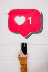 Someone holding up a phone against a wall with an instagram like notification printed on it